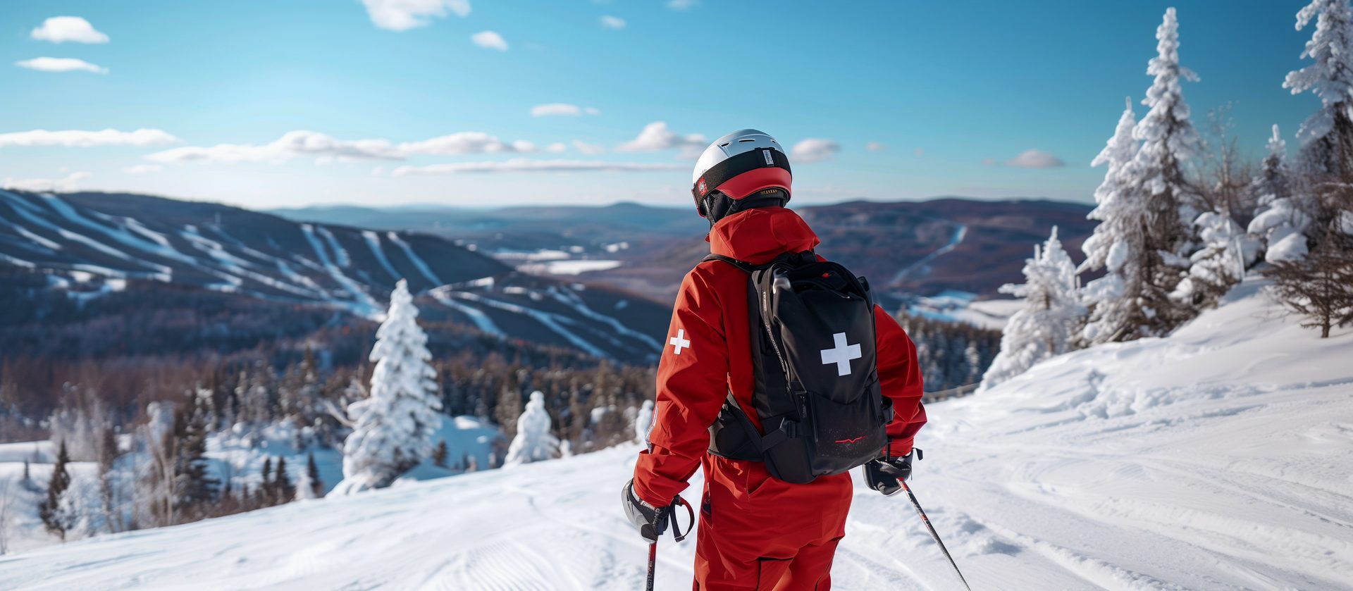 Patrouilleur de l'INSQ, de dos, contemplant les pistes enneigées d'une station de ski au Québec